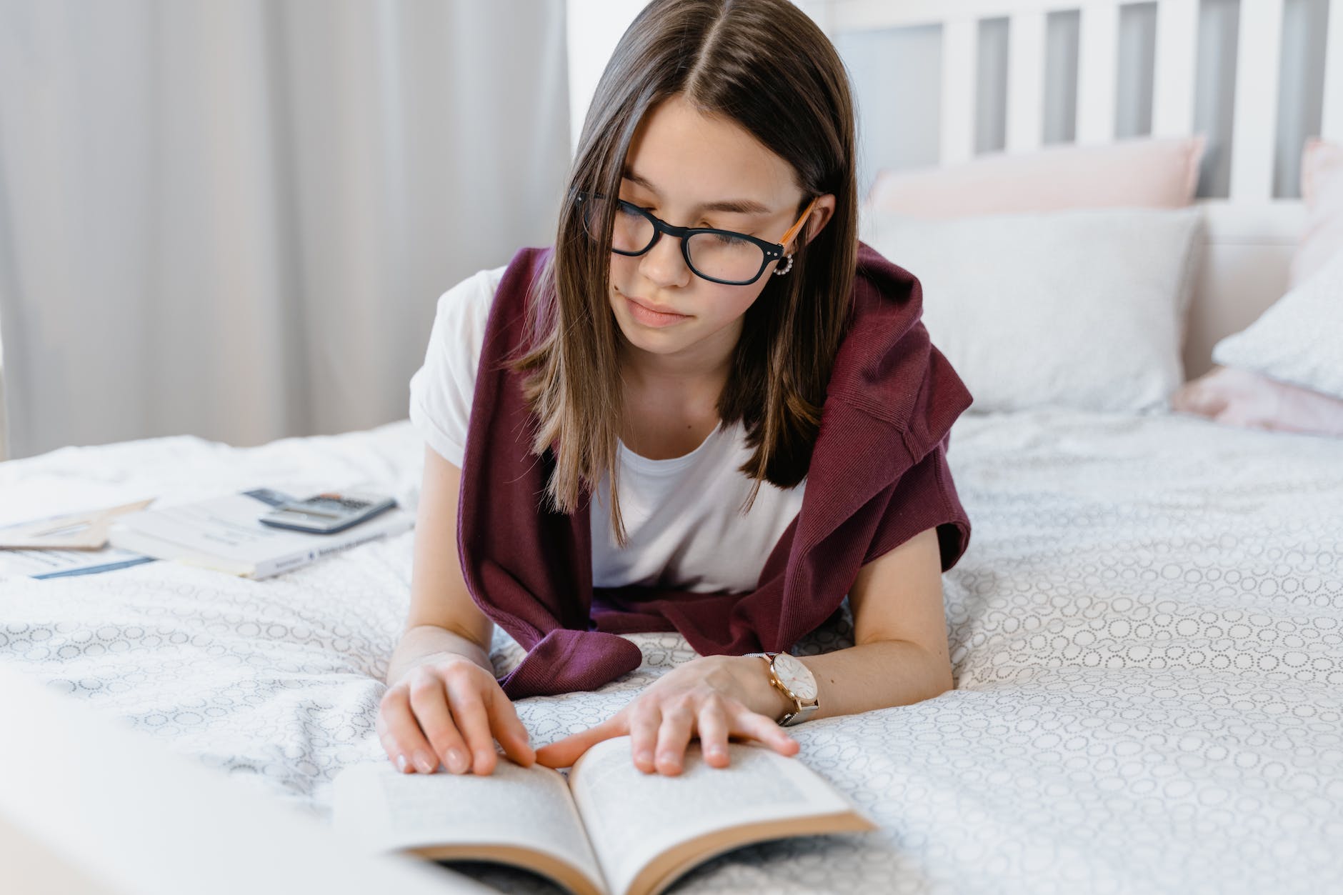 a girl wearing eyeglasses while reading a book